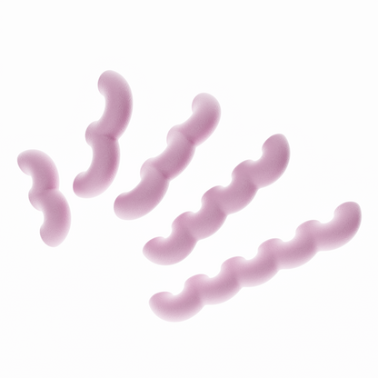 Une vue de présentation de cinq poignées de meubles ondulées en rose pastel, disposées en diagonale par ordre de taille croissant sur un fond blanc pur. Cette image illustre clairement les cinq différentes longueurs disponibles dans la collection. Leur texture est mate et légèrement granuleuse, typique du biopolymère.
