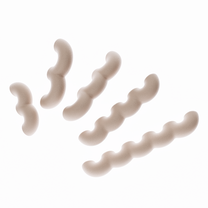 Une vue de présentation de cinq poignées de meubles ondulées en marron clair, disposées en diagonale par ordre de taille croissant sur un fond blanc pur. Cette image illustre clairement les cinq différentes longueurs disponibles dans la collection. Leur texture est mate et légèrement granuleuse, typique du biopolymère.