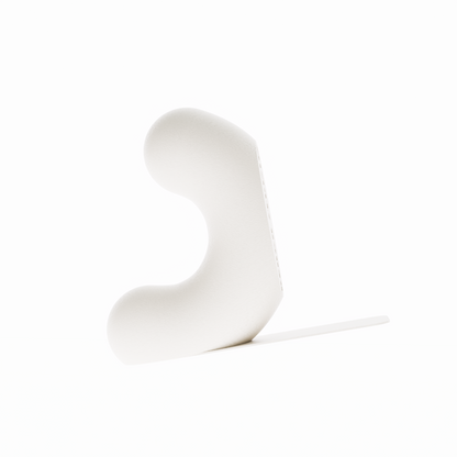Un serre-livre design de la marque Benga Studio, de couleur beige. L'objet moderne a une forme de U stylisé, avec une hauteur de 15 cm. Il est présenté sur un fond blanc pur, avec une languette de support  mince et horizontal s'étendant à droite pour supporter des grands livres. Le serre-livre a une texture fine, lisse et mate. Il est conçu pour maintenir des livres lourds de manière discrète et élégante.